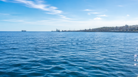 Mar abierto con puerto y barcos al fondo.